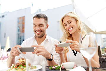 Image showing happy couple with smatphone photographing food