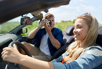 Image showing man photographing woman driving car by film camera