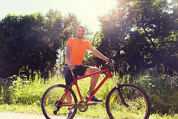 Image showing happy young man riding bicycle outdoors