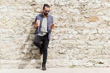 Image showing man with smartphone drinking coffee on city street