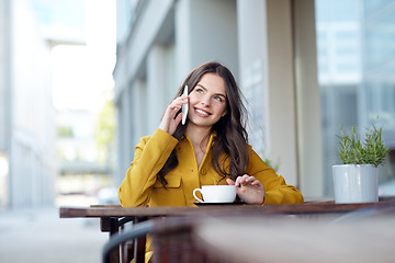 Image showing happy woman calling on smartphone at city cafe