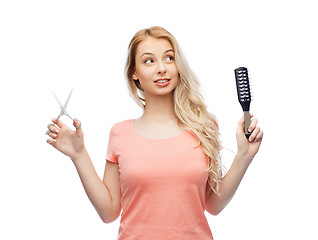 Image showing young woman with scissors and hairbrush