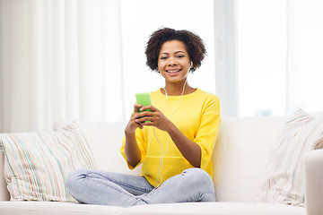 Image showing happy african woman with smartphone and earphones