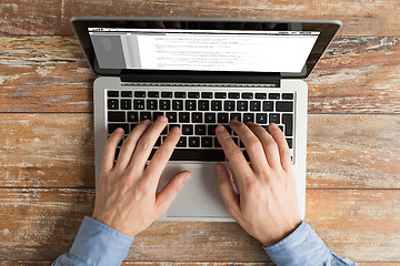 Image showing close up of male hands with laptop typing