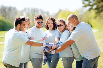 Image showing group of volunteers putting hands on top in park