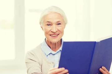 Image showing happy smiling senior woman reading book at home