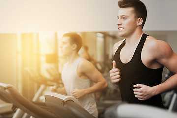 Image showing smiling men exercising on treadmill in gym