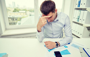 Image showing stressed businessman with papers in office