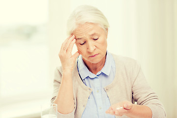 Image showing senior woman with water and medicine at home