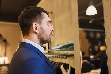 Image showing man in jacket looking to mirror at clothing store