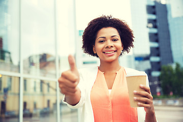 Image showing happy woman with coffee showing thumbs up in city