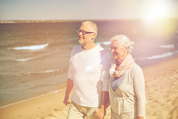 Image showing happy senior couple walking along summer beach