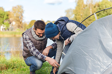 Image showing happy father and son setting up tent outdoors