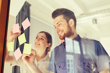 Image showing happy creative team writing on stickers at office