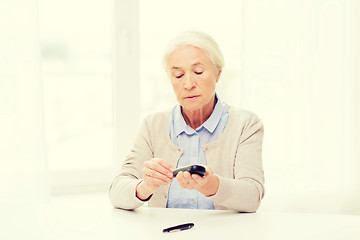 Image showing senior woman with glucometer checking blood sugar