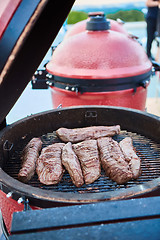 Image showing thick strip steak being grilled outdoors. Shallow dof