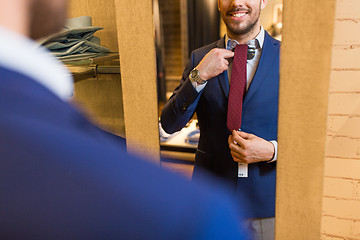 Image showing close up of man trying tie on at mirror
