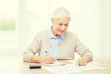 Image showing senior woman with papers and calculator at home