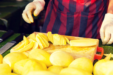 Image showing close up of cook hands and mango at street market