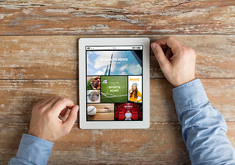 Image showing close up of male hands to tablet pc on table