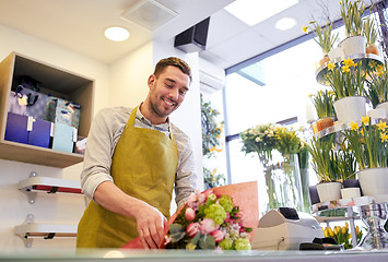 Image showing florist wrapping flowers in paper at flower shop