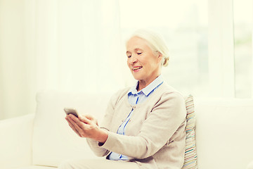 Image showing senior woman with smartphone texting at home