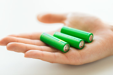 Image showing close up of hand holding green alkaline batteries