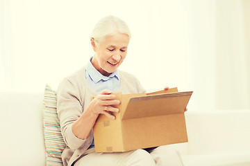 Image showing happy senior woman with parcel box at home