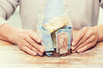 Image showing close up of senior woman with money in glass jar