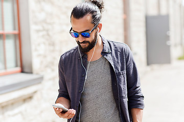 Image showing man with earphones and smartphone walking in city