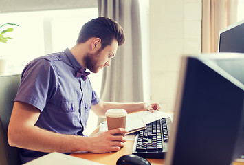 Image showing creative male worker drinking coffee and reading