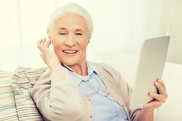 Image showing senior woman with tablet pc and earphones at home