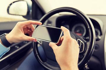 Image showing close up of man hand with smartphone driving car