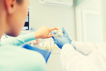 Image showing close up of dentist with teeth model and patient