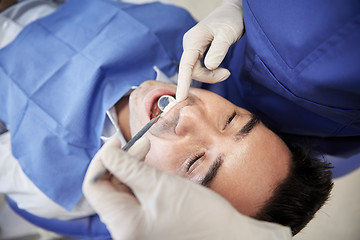 Image showing close up of dentist checking male patient teeth