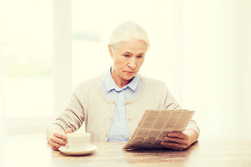 Image showing senior woman with coffee reading newspaper at home