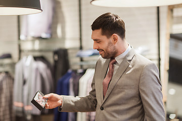 Image showing happy young man choosing bow-tie in clothing store