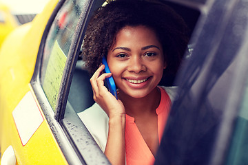 Image showing happy african woman calling on smartphone in taxi