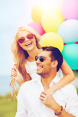 Image showing couple with colorful balloons at seaside