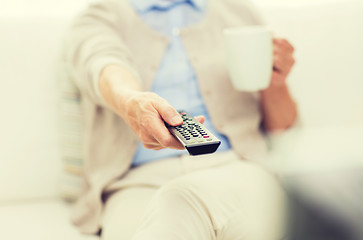 Image showing senior woman watching tv and drinking tea at home