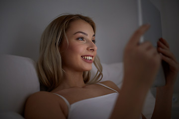 Image showing young woman with tablet pc in bed at home bedroom