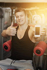 Image showing smiling young man with smartphone in gym