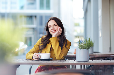 Image showing happy woman drinking cocoa at city street cafe