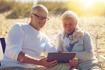 Image showing happy senior couple with tablet pc on summer beach