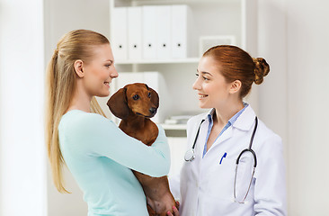 Image showing happy woman with dog and doctor at vet clinic