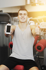 Image showing smiling young man with smartphone in gym