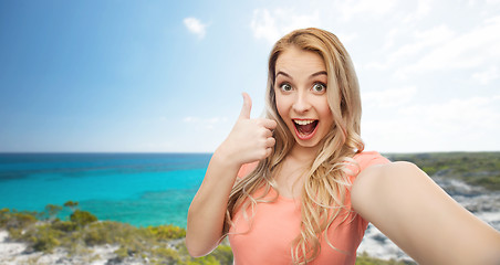 Image showing happy woman taking selfie and showing thumbs up