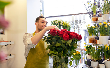 Image showing smiling florist man with roses at flower shop