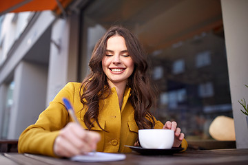 Image showing happy woman with notebook drinking cocoa at cafe