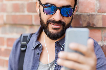 Image showing man with earphones and smartphone on city street